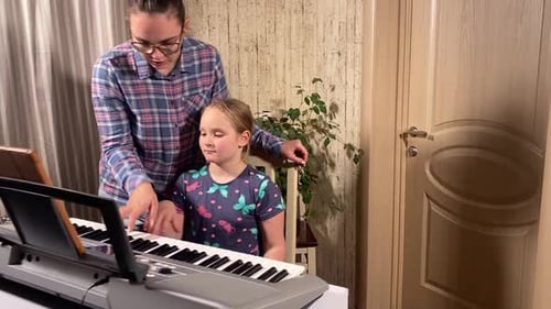 Girl Learns Piano with Teacher in Home Setting