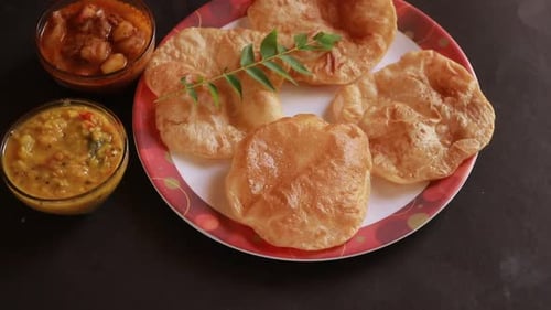 rotation Chole Bhature or Chick pea curry and Fried Puri served in terracotta crockery over back bac