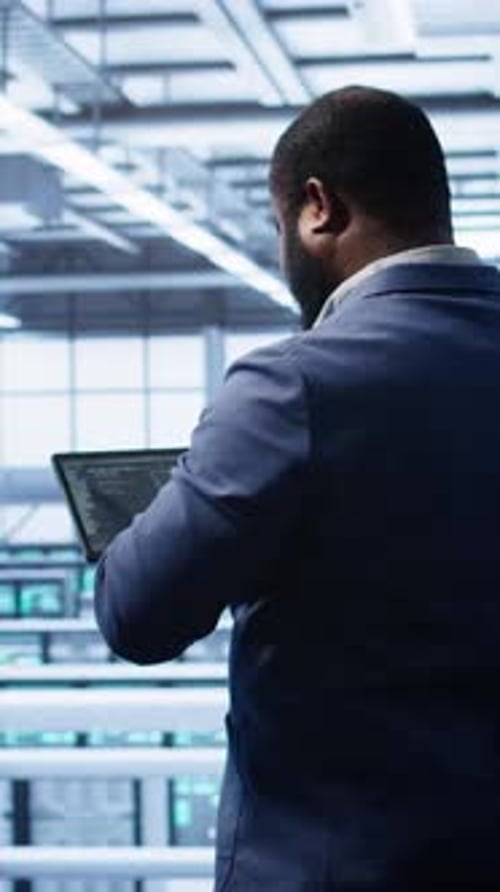 Vertical Video IT Expert in Server Hub Facility Looking for Network Bugs with Tablet