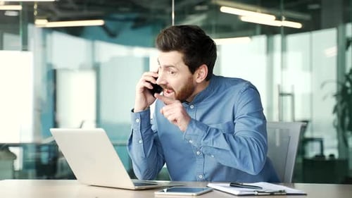 Angry dissatisfied manager arguing talking on phone while sitting at workplace in business office.