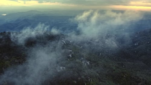 Drohne fliegt durch Wolken und Morgennebel hoch oben in der Bergkette