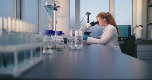 Scientist Working at Microscope in Bright Laboratory