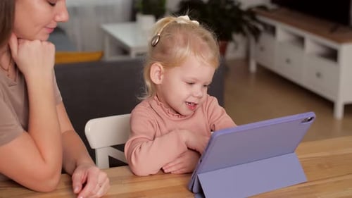 A Child with Cochlear Implants Plays with a Tablet Computer with His Mother