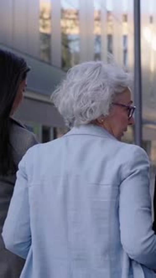 Three Businesswomen Walk and Talk Together Outside Their Office Building