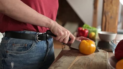 Person Slicing Yellow Bell Pepper in Kitchen