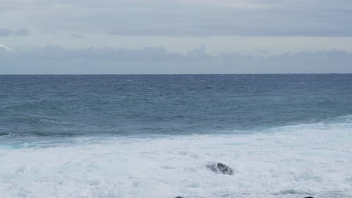 Ocean horizon with foamy waves under cloudy sky