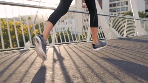 Fitness woman running and jogging on a bridge in the city outdoors