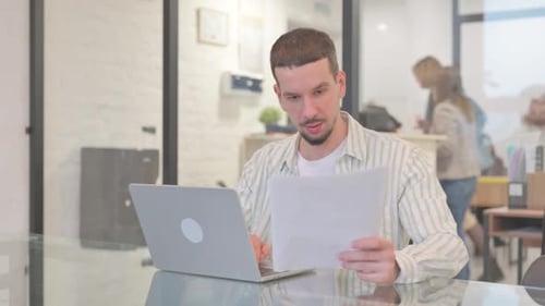 Excited Man Working on Laptop in Bright Office