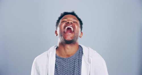 4k video footage of a young man laughing against a grey studio background
