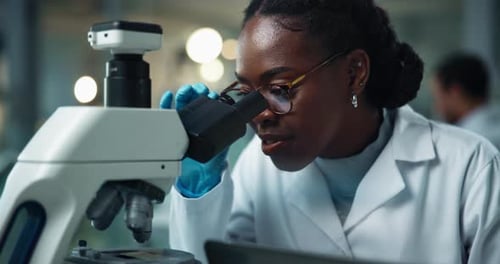 Young Woman Scientist Working with Microscope in Lab
