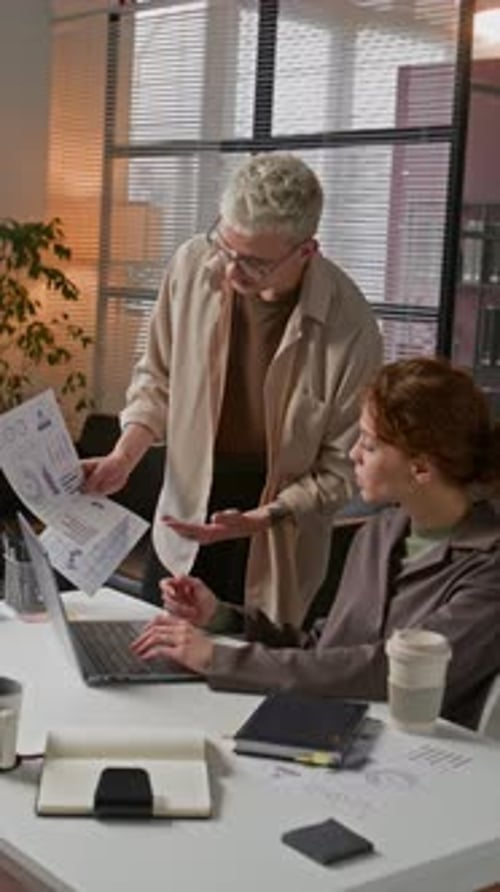 Young Man and Woman Discussing Charts At Work In Office