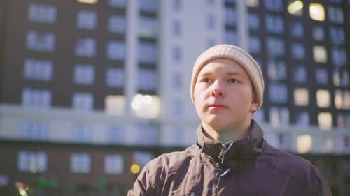 Thoughtful Man in Winter Attire Observing City Skyline at Dusk Somber Man with Beanie and Jacket