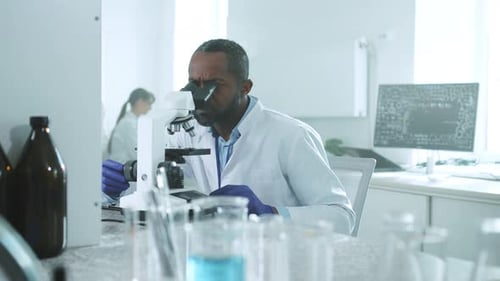 Dedicated Scientist Analyzing Sample Under Microscope in Lab