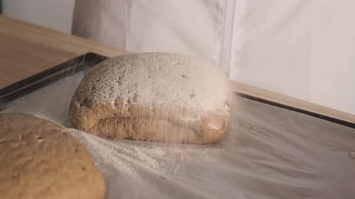 Dusting Flour on Loaves of Bread on Baking Sheet
