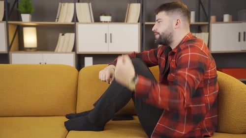 Man Sitting on Couch Gesturing While Talking