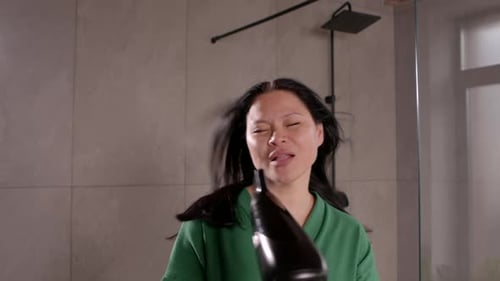 Woman Dries Hair in Bathroom with Hair Dryer