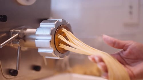 Male cook accompany the long strands of spaghetti from the pasta Close up shot