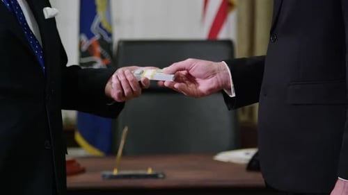 Underhanded Businessmen Exchange Stack of Cash and Shake Hands