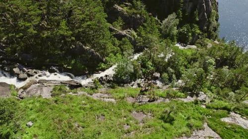 Drone View Of Waterfall Flowing Over Rocky Terrain And Tree-Lined Slopes