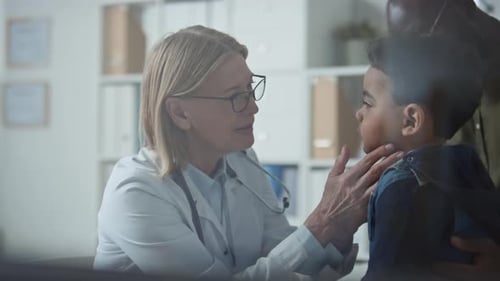 Doctor Examines Young Boy's Throat in Clinic