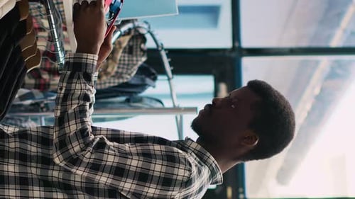 Young Adult Browsing Clothes in Clothing Store