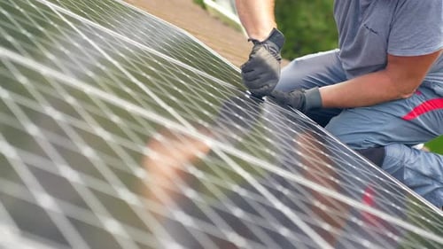 Closeup of Solar Panel technician installing photovoltaic cells on rooftop