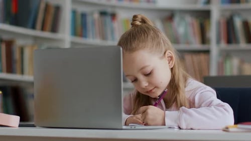 Diligent Girl Studies with Laptop in School Library