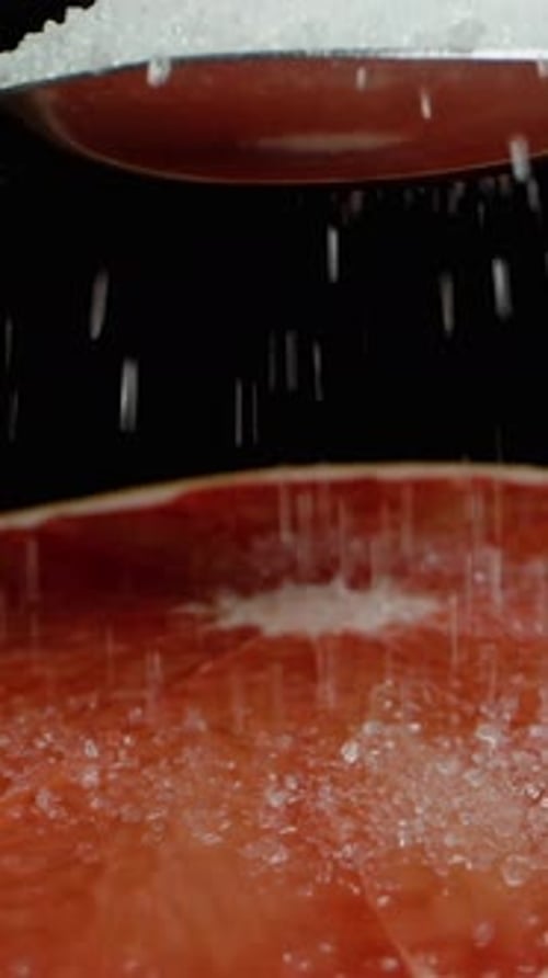 Vertical video. They pour a whole spoonful of sugar onto half a grapefruit. Dolly slider.