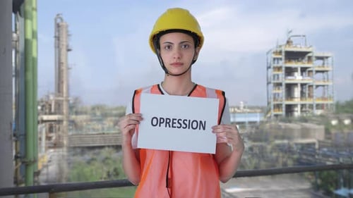 Sad Indian female construction worker holding OPPRESSION banner