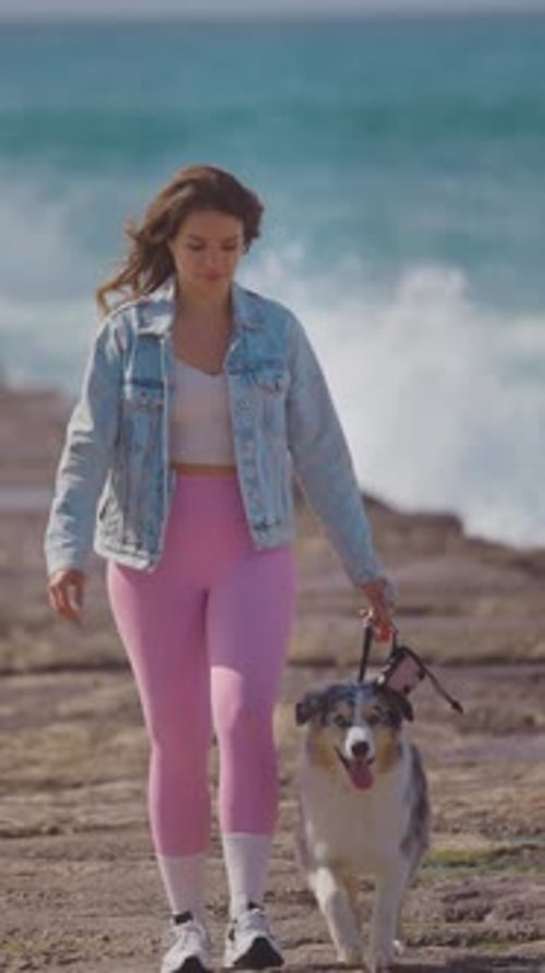 Young Woman Walking Her Australian Shepherd on a Rocky Beach