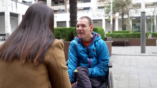 Man in wheelchair talking to woman outdoors