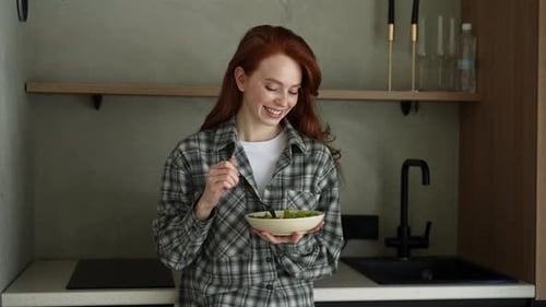 Portrait of Young Happy Woman Eating Green Salad Standing in Kitchen at Home Attractive Beautiful