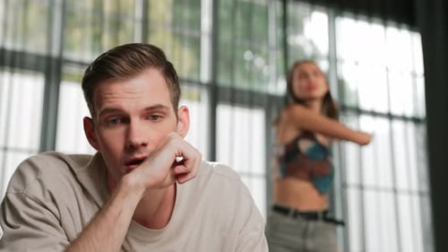 Man Bored as Woman Dances in the Background