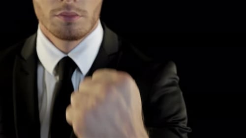 Man in Suit Makes a Fist Against Black