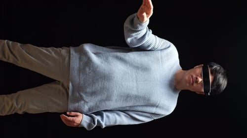 Asiatischer Mann berührt und wischt virtuelle Realität mit der Hand, während er eine futuristische Brille benutzt