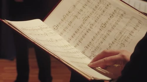 Escenista de ópera sosteniendo un libro de música con notas musicales, partitura