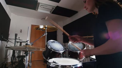 Young Woman Playing Drums in the Studio