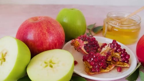 Jewish Holiday Rosh Hashana Food with Honey Pomegranate and Apples on Pink Background
