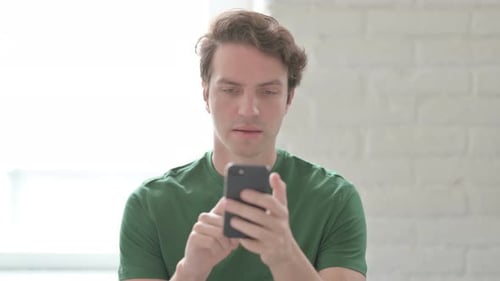 Man Looks at Phone and Reacts Victoriously