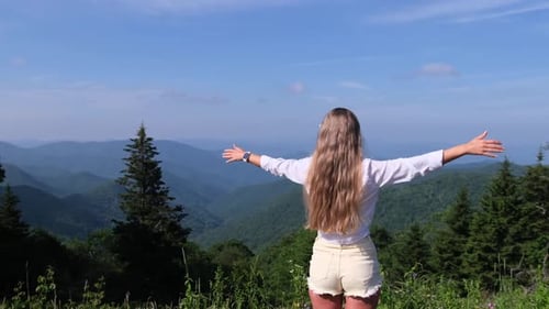 A Woman Spreads Her Arms Wide As She Enjoys the Beauty of the Surrounding Mountain Landscape