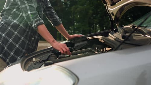 Breakdown of the car open the hood of the car girl driver checks the condition of the engine while