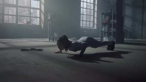 Athletic woman fitness training push ups strength workout in dark loft gym