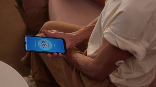 Top View of Senior Woman Holding Smartphone with Diabetes Tracking App