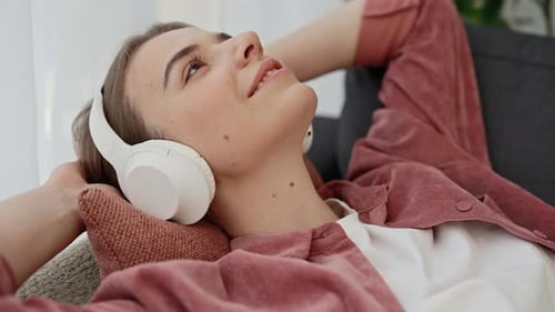 Side View of the Beautiful Caucasian Woman is Resting After Studying Lying on the Sofa and Enjoying