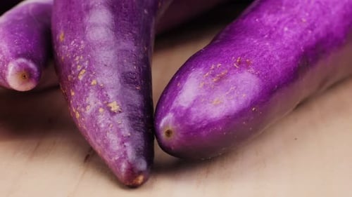 A Violet Eggplant is Placed on a Wooden Cutting Board Showcasing the Beauty of This Terrestrial