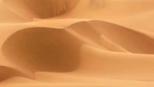 Luftaufnahme von weichem Sand mit Sonnenschein, der sich auf der goldenen Oberfläche der Dünen spiegelt