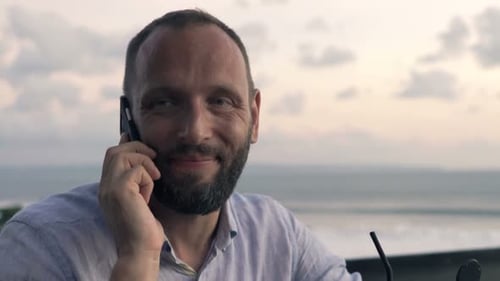 Man Talking On Cellphone And Drinking Cocktail On Terrace In Bar
