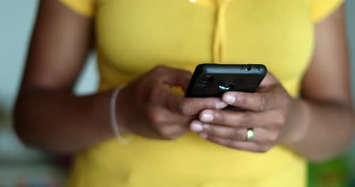 Woman Smiles While Texting on Smartphone Indoors