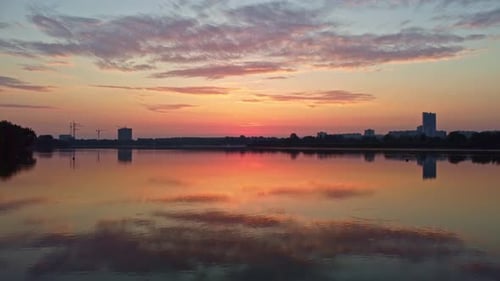Sonnenaufgang am Fluss mit Wolken, die sich im Wasser spiegeln