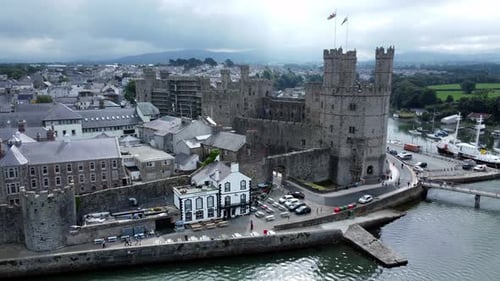 Ancient Caernarfon castle Welsh harbour town aerial view medieval waterfront landmark slow right ove